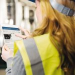 Woman_wearing_reflective_vest_controlling_industrial_plant_with_digital_tablet