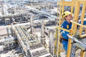 chemical_industry_plant_-_workers_in_work_clothes_in_a_refinery_with_pipes_and_machinery__Adobe_Stock_-_Industrieblick